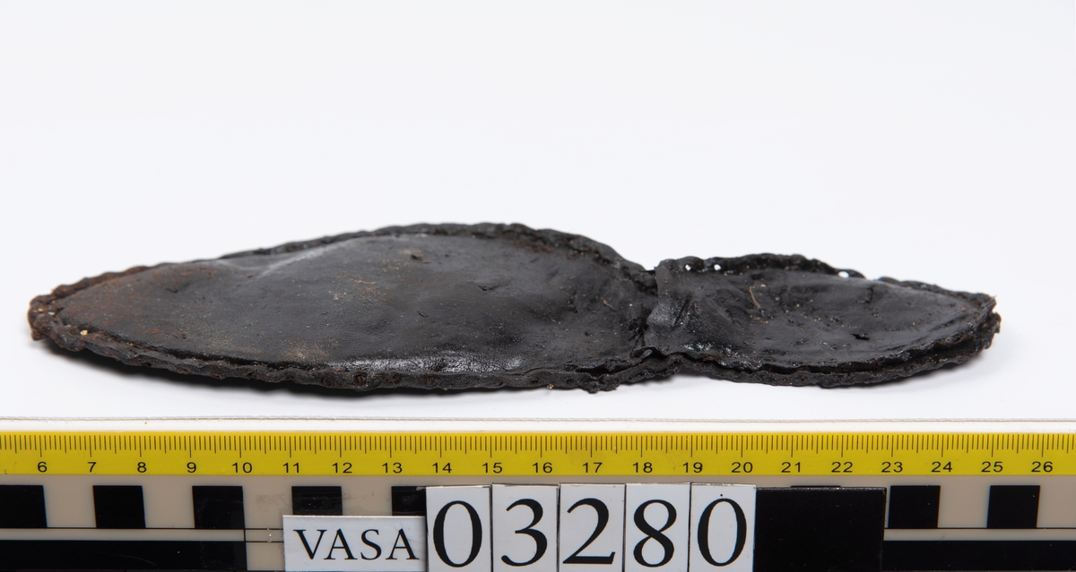 Tjugofem delar och fragment från stövel.
En sula, fyndnummer 03280. På sulans ovansida syns intryck av bindtråd. Runt ytterkanterna löper stygnshål. I hälpartiet finns hål efter träpligg.
Del av en klack, fyndnummer 03280:1, i form av fyra klacklappar samt kvarsittande träpligg.
En stropp, fyndnummer 03280:2. Ena änden är spetsformad. Andra änden är något fragmentarisk. I bägge ändar finns hål efter stygn.
Tre delar från stövelskaftet i form av tre läderstycken. Lädrstyckena är spaltade och ligger vikta. Längs sidorna löper stygnshål.
Delar och fragment av sulor, inlägg, ovanläder mm.
Merparten av lädret är spaltat och något kladdigt.