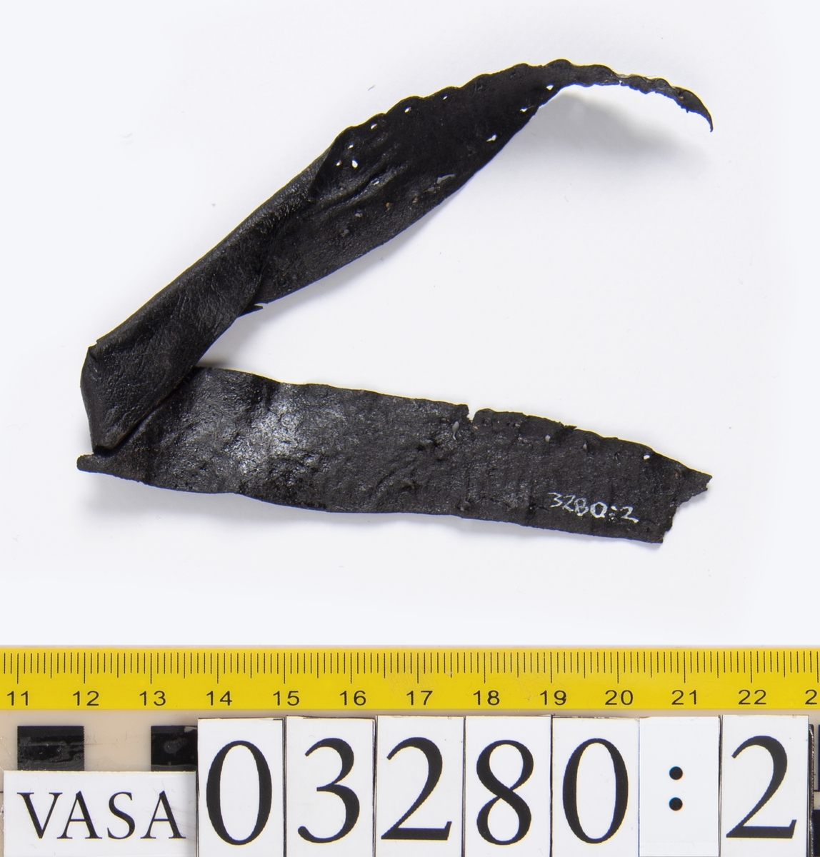 Tjugofem delar och fragment från stövel.
En sula, fyndnummer 03280. På sulans ovansida syns intryck av bindtråd. Runt ytterkanterna löper stygnshål. I hälpartiet finns hål efter träpligg.
Del av en klack, fyndnummer 03280:1, i form av fyra klacklappar samt kvarsittande träpligg.
En stropp, fyndnummer 03280:2. Ena änden är spetsformad. Andra änden är något fragmentarisk. I bägge ändar finns hål efter stygn.
Tre delar från stövelskaftet i form av tre läderstycken. Lädrstyckena är spaltade och ligger vikta. Längs sidorna löper stygnshål.
Delar och fragment av sulor, inlägg, ovanläder mm.
Merparten av lädret är spaltat och något kladdigt.