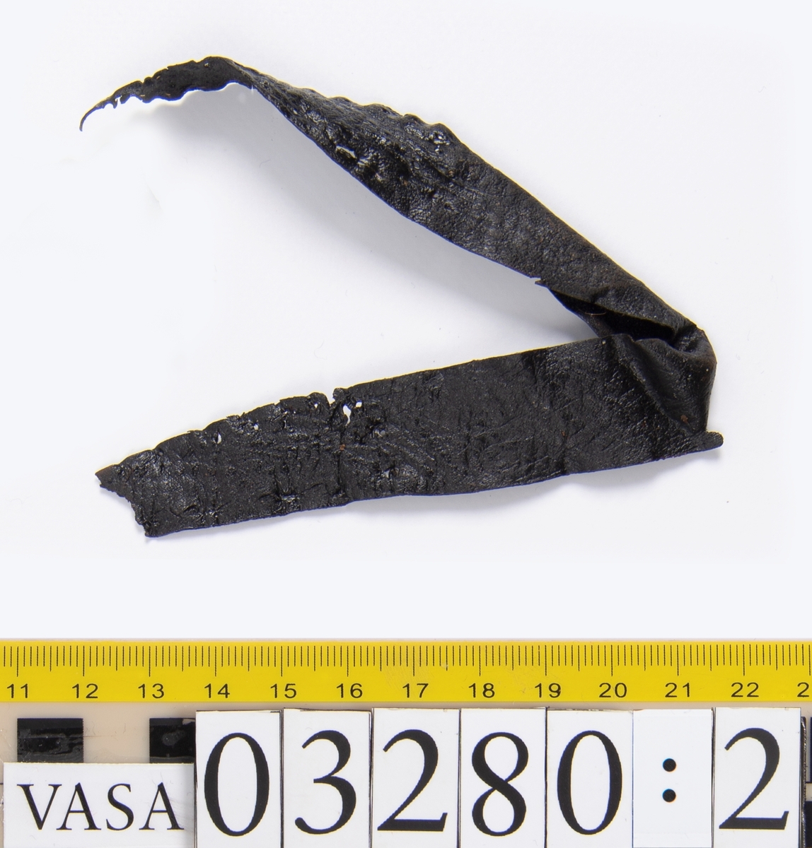 Tjugofem delar och fragment från stövel.
En sula, fyndnummer 03280. På sulans ovansida syns intryck av bindtråd. Runt ytterkanterna löper stygnshål. I hälpartiet finns hål efter träpligg.
Del av en klack, fyndnummer 03280:1, i form av fyra klacklappar samt kvarsittande träpligg.
En stropp, fyndnummer 03280:2. Ena änden är spetsformad. Andra änden är något fragmentarisk. I bägge ändar finns hål efter stygn.
Tre delar från stövelskaftet i form av tre läderstycken. Lädrstyckena är spaltade och ligger vikta. Längs sidorna löper stygnshål.
Delar och fragment av sulor, inlägg, ovanläder mm.
Merparten av lädret är spaltat och något kladdigt.