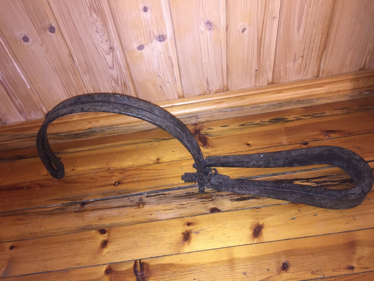 Revesaks i metall. To bogar, festa saman av ei metallbøyle. Ei metallfjør. 