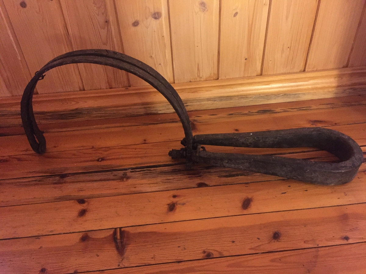 Revesaks i metall. To bogar, festa saman av ei metallbøyle. Ei metallfjør. 