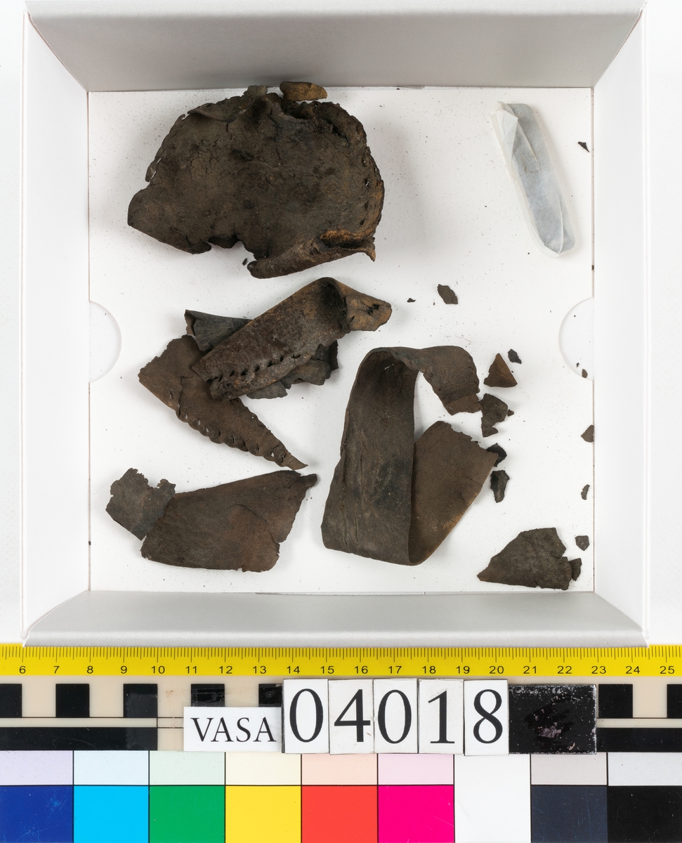 Tolv fragment av sko, varav två fragment kan vara delar från en slejf.
Lädret är mycket sprött och hårt.