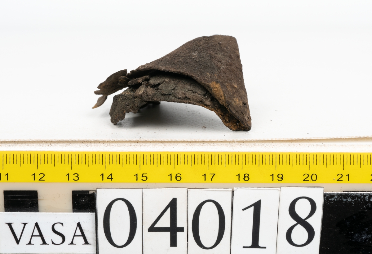 Tolv fragment av sko, varav två fragment kan vara delar från en slejf.
Lädret är mycket sprött och hårt.