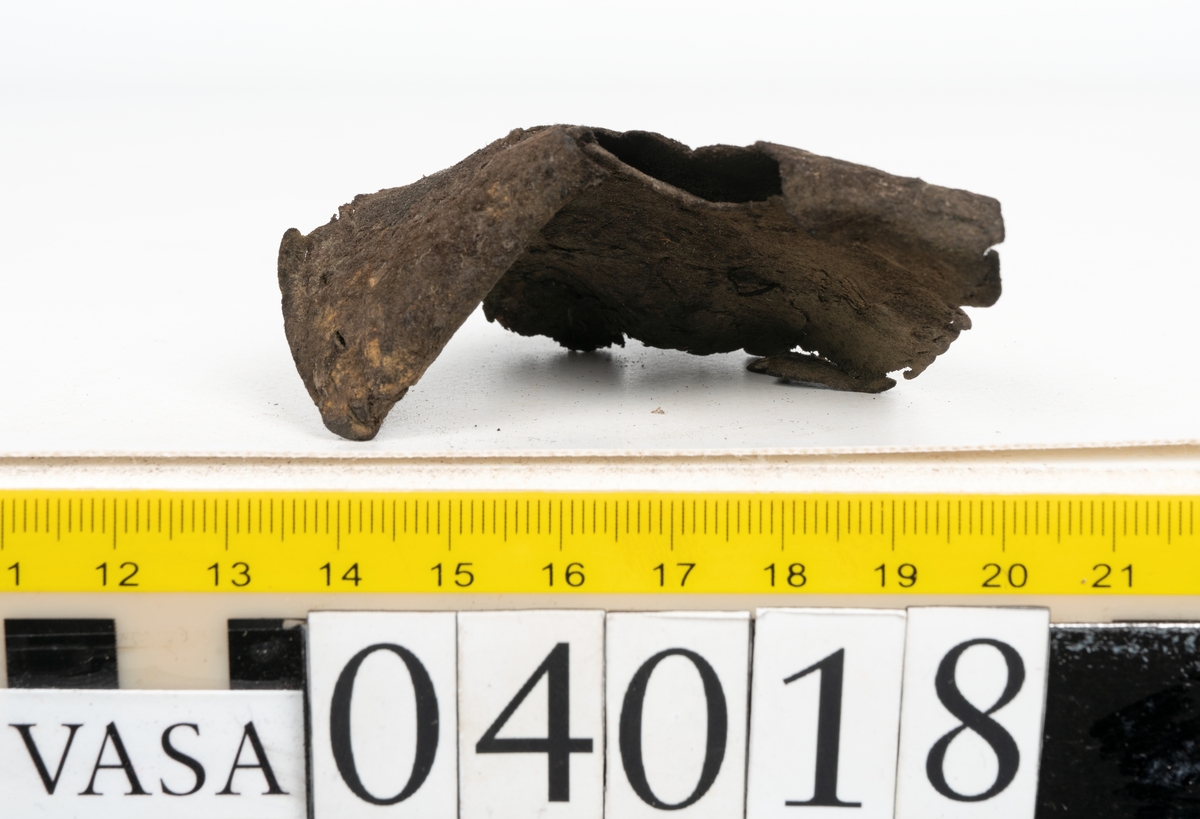 Tolv fragment av sko, varav två fragment kan vara delar från en slejf.
Lädret är mycket sprött och hårt.