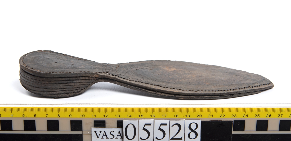 Dokumentation 1997:
Ett tjugotal delar och fragment från ett par skor.
Del av en skobotten, fyndnummer 05528. Skobottnen består av två sulor mellan vilka klacklappar sitter fästade. Sulorna och klacklapparna har monterats samman med tråd av konserveringsenheten.
En klack, fyndnummer 05528:1. Klacken är uppbyggd av sju klacklappar. Klacken har monterats samman med tråd av konserveringsenheten.
Två sulor, fyndnummer 05528:2 samt 05528:3. Sula fyndnummer 05528:3 har ett nedslitet hälparti. Sulorna och klacken är delar från den andra skobottnen som bildar par med skobotten fyndnummer 05528.
Två sulor, fyndnummer 05528:4 och 05528:5. Sulorna hör samman med någon av de två ovan nämnda skobottnarna.
Ett sidosycke med slejf, fyndnummer 05528:6. Längs med sidostyckets nedre kant löper stygnshål.
Ett 15-tal delar och fragment av holtrand, sulor mm.
Lädret är kraftigt och välbevarat.

Dokumentation 2022:
Fragment från ovanläder och ett par skobottnar (05528:4). Framstycke och sulor till öppna randskor. Tillverkade i läder. Skapades på en rak läst och bars på höger fot. Det finns regelbundna skurna dekorationer på framstycket. Klacken är reparerad med en läderlapp under sulan. Det finns tecken på delaminering på framstycket. Det finns hål i skobottens sidor och i mittensulan. Det finns inga tecken på lagningar.
För mer information, se Uppritning under Länkade filer.

Text in english:
These are one vamp fragment and a pair of bottom units (05528:4) of open side latchet shoes, made of leather, of randed construction with a patch heel, made on a straight last and worn on the right foot, with decorative pinked features across the vamp. The vamps are delaminated, and the bottom unit presents holes on both lateral sides and on the midsole. There are no signs of repairs.
For more information, go to Länkade filer: Uppritning