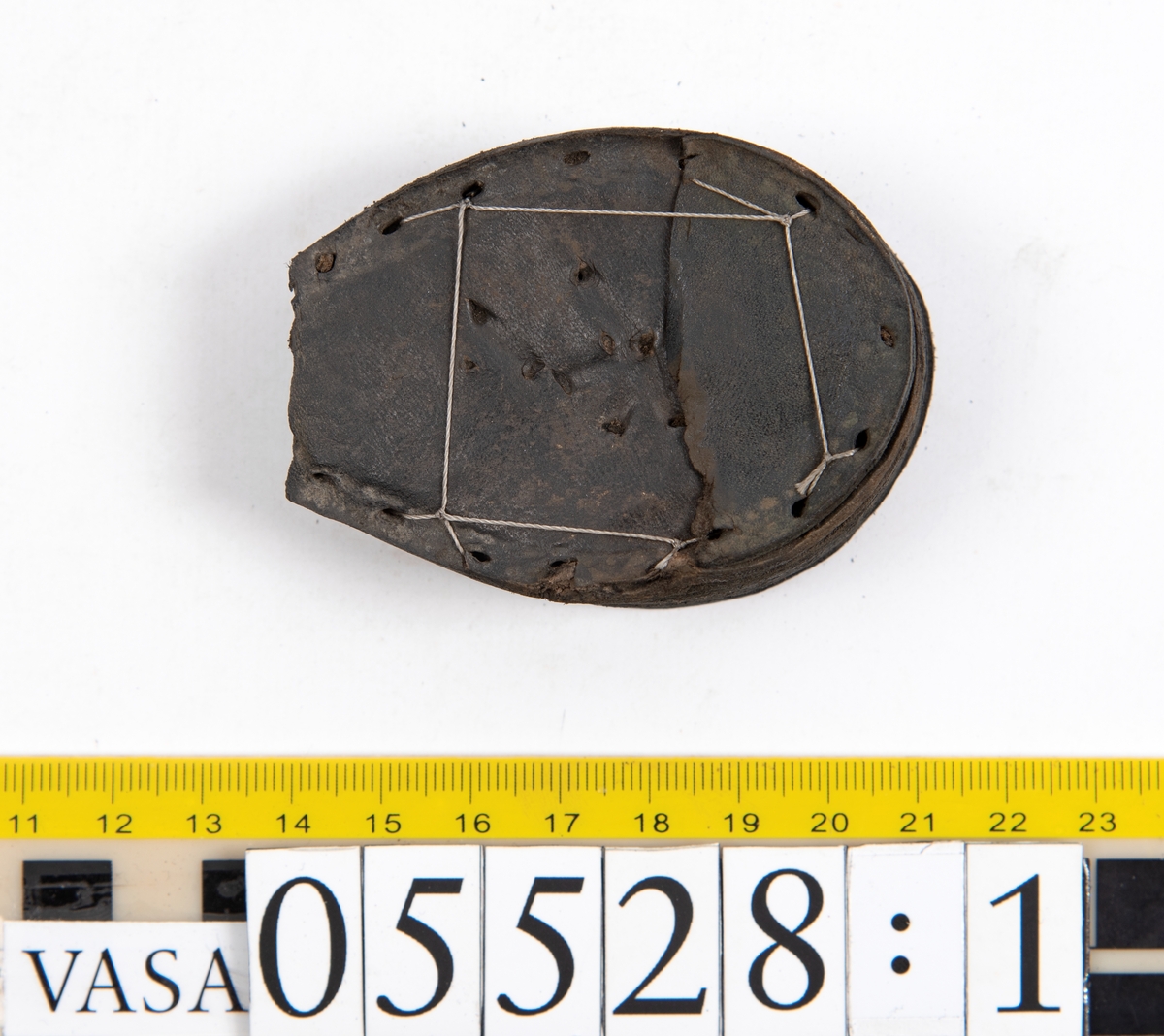 Dokumentation 1997:
Ett tjugotal delar och fragment från ett par skor.
Del av en skobotten, fyndnummer 05528. Skobottnen består av två sulor mellan vilka klacklappar sitter fästade. Sulorna och klacklapparna har monterats samman med tråd av konserveringsenheten.
En klack, fyndnummer 05528:1. Klacken är uppbyggd av sju klacklappar. Klacken har monterats samman med tråd av konserveringsenheten.
Två sulor, fyndnummer 05528:2 samt 05528:3. Sula fyndnummer 05528:3 har ett nedslitet hälparti. Sulorna och klacken är delar från den andra skobottnen som bildar par med skobotten fyndnummer 05528.
Två sulor, fyndnummer 05528:4 och 05528:5. Sulorna hör samman med någon av de två ovan nämnda skobottnarna.
Ett sidosycke med slejf, fyndnummer 05528:6. Längs med sidostyckets nedre kant löper stygnshål.
Ett 15-tal delar och fragment av holtrand, sulor mm.
Lädret är kraftigt och välbevarat.

Dokumentation 2022:
Fragment från ovanläder och ett par skobottnar (05528:4). Framstycke och sulor till öppna randskor. Tillverkade i läder. Skapades på en rak läst och bars på höger fot. Det finns regelbundna skurna dekorationer på framstycket. Klacken är reparerad med en läderlapp under sulan. Det finns tecken på delaminering på framstycket. Det finns hål i skobottens sidor och i mittensulan. Det finns inga tecken på lagningar.
För mer information, se Uppritning under Länkade filer.

Text in english:
These are one vamp fragment and a pair of bottom units (05528:4) of open side latchet shoes, made of leather, of randed construction with a patch heel, made on a straight last and worn on the right foot, with decorative pinked features across the vamp. The vamps are delaminated, and the bottom unit presents holes on both lateral sides and on the midsole. There are no signs of repairs.
For more information, go to Länkade filer: Uppritning