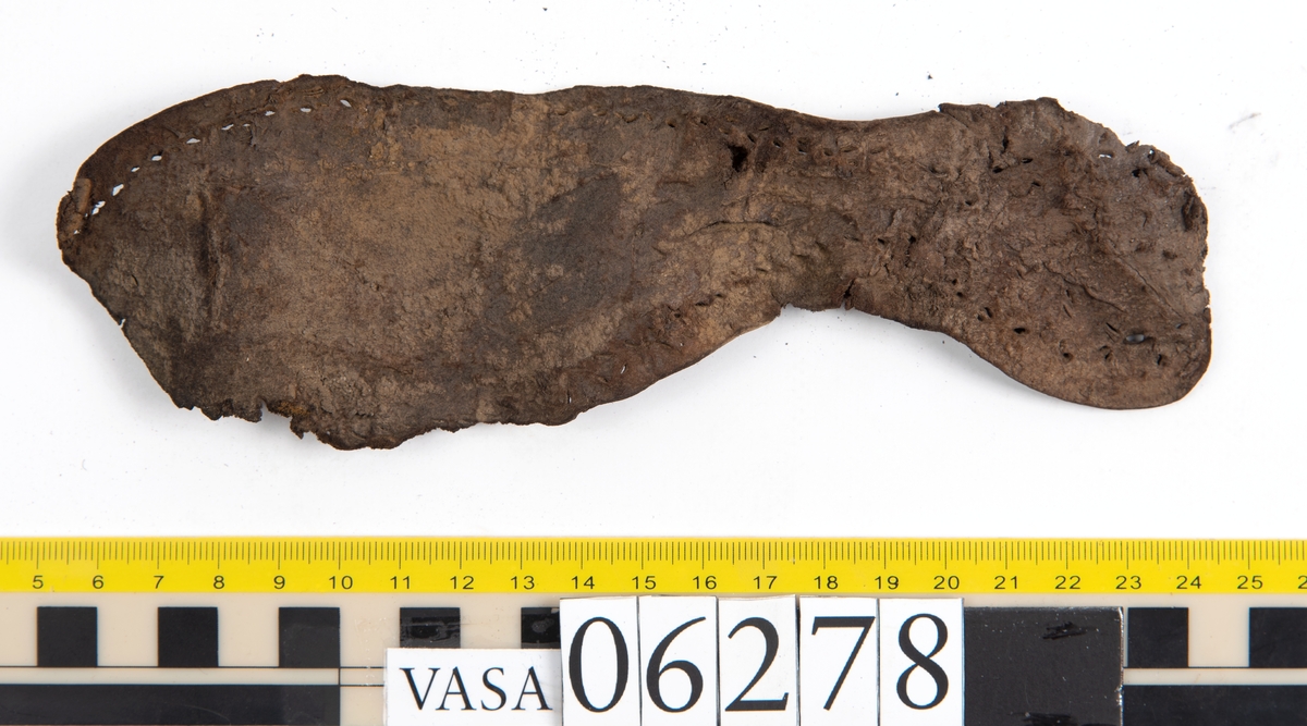 Sula, klacklapp samt större och mindre fragment från skobotten. Totalt ett 50-tal delar och fragment. Sulan är något fragmentarisk samt försedd med en ritsad linje som löper innanför ytterkanten. På klacklappen syns hål efter träpligg.
Klacklädret och sullädret är torrt och styvt medan en stor del av fragmenten består av mjukt och böjligt läder.