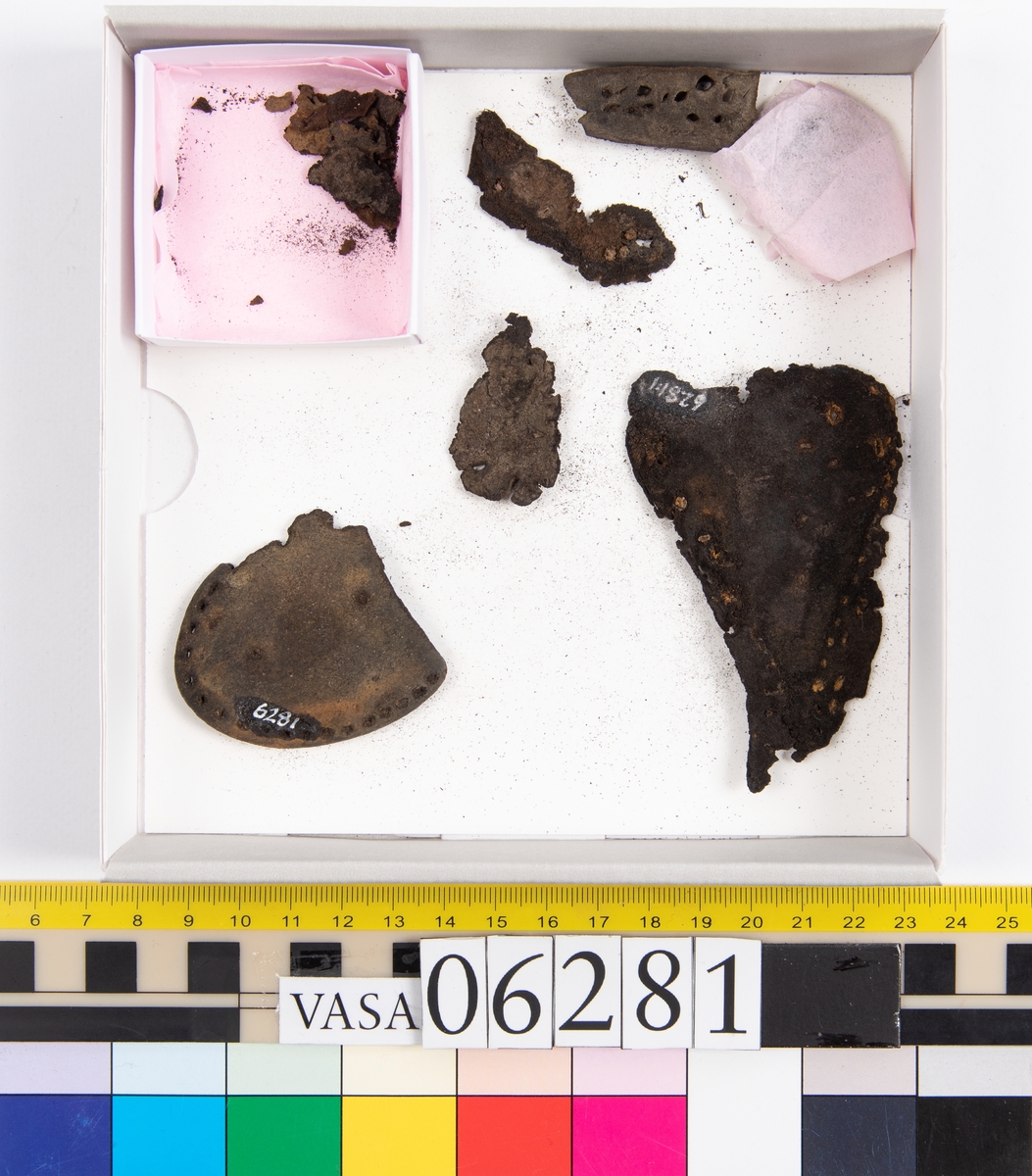 Delar och fragment av skobotten: klacklapp, del av sula samt tretton mindre fragment.

Klacklappen fyndnummer 06281, har hål efter två träpligg. Lädret är kraftigt. Del av sula med kvarsittande träpligg, fyndnummer 06281:1. Längs med sulans ytterkant löper dubbla rader av stygnshål. De fem fragmenten härrör troligtvis från sulor.

Lädret är rostfärgat och mycket sprött.
