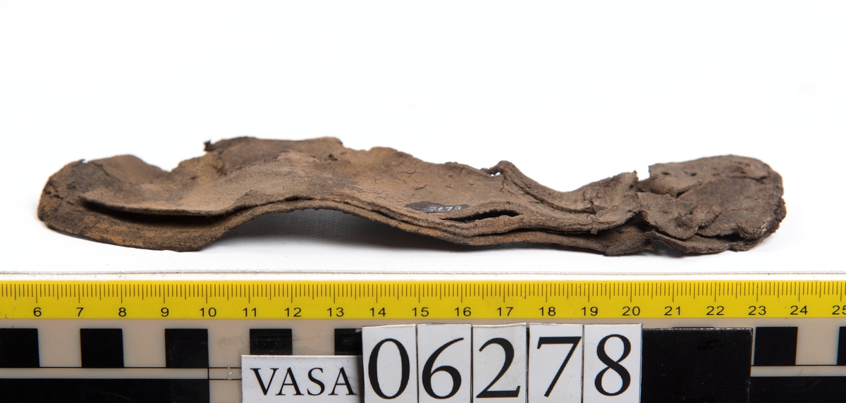 Sula, klacklapp samt större och mindre fragment från skobotten. Totalt ett 50-tal delar och fragment. Sulan är något fragmentarisk samt försedd med en ritsad linje som löper innanför ytterkanten. På klacklappen syns hål efter träpligg.
Klacklädret och sullädret är torrt och styvt medan en stor del av fragmenten består av mjukt och böjligt läder.