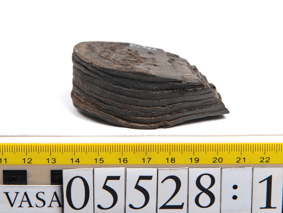 Dokumentation 1997:
Ett tjugotal delar och fragment från ett par skor.
Del av en skobotten, fyndnummer 05528. Skobottnen består av två sulor mellan vilka klacklappar sitter fästade. Sulorna och klacklapparna har monterats samman med tråd av konserveringsenheten.
En klack, fyndnummer 05528:1. Klacken är uppbyggd av sju klacklappar. Klacken har monterats samman med tråd av konserveringsenheten.
Två sulor, fyndnummer 05528:2 samt 05528:3. Sula fyndnummer 05528:3 har ett nedslitet hälparti. Sulorna och klacken är delar från den andra skobottnen som bildar par med skobotten fyndnummer 05528.
Två sulor, fyndnummer 05528:4 och 05528:5. Sulorna hör samman med någon av de två ovan nämnda skobottnarna.
Ett sidosycke med slejf, fyndnummer 05528:6. Längs med sidostyckets nedre kant löper stygnshål.
Ett 15-tal delar och fragment av holtrand, sulor mm.
Lädret är kraftigt och välbevarat.

Dokumentation 2022:
Fragment från ovanläder och ett par skobottnar (05528:4). Framstycke och sulor till öppna randskor. Tillverkade i läder. Skapades på en rak läst och bars på höger fot. Det finns regelbundna skurna dekorationer på framstycket. Klacken är reparerad med en läderlapp under sulan. Det finns tecken på delaminering på framstycket. Det finns hål i skobottens sidor och i mittensulan. Det finns inga tecken på lagningar.
För mer information, se Uppritning under Länkade filer.

Text in english:
These are one vamp fragment and a pair of bottom units (05528:4) of open side latchet shoes, made of leather, of randed construction with a patch heel, made on a straight last and worn on the right foot, with decorative pinked features across the vamp. The vamps are delaminated, and the bottom unit presents holes on both lateral sides and on the midsole. There are no signs of repairs.
For more information, go to Länkade filer: Uppritning