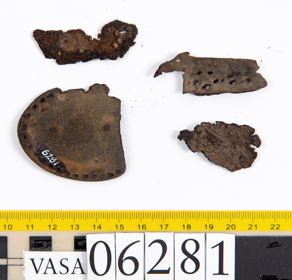 Delar och fragment av skobotten: klacklapp, del av sula samt tretton mindre fragment.

Klacklappen fyndnummer 06281, har hål efter två träpligg. Lädret är kraftigt. Del av sula med kvarsittande träpligg, fyndnummer 06281:1. Längs med sulans ytterkant löper dubbla rader av stygnshål. De fem fragmenten härrör troligtvis från sulor.

Lädret är rostfärgat och mycket sprött.