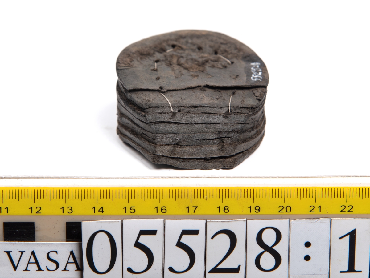 Dokumentation 1997:
Ett tjugotal delar och fragment från ett par skor.
Del av en skobotten, fyndnummer 05528. Skobottnen består av två sulor mellan vilka klacklappar sitter fästade. Sulorna och klacklapparna har monterats samman med tråd av konserveringsenheten.
En klack, fyndnummer 05528:1. Klacken är uppbyggd av sju klacklappar. Klacken har monterats samman med tråd av konserveringsenheten.
Två sulor, fyndnummer 05528:2 samt 05528:3. Sula fyndnummer 05528:3 har ett nedslitet hälparti. Sulorna och klacken är delar från den andra skobottnen som bildar par med skobotten fyndnummer 05528.
Två sulor, fyndnummer 05528:4 och 05528:5. Sulorna hör samman med någon av de två ovan nämnda skobottnarna.
Ett sidosycke med slejf, fyndnummer 05528:6. Längs med sidostyckets nedre kant löper stygnshål.
Ett 15-tal delar och fragment av holtrand, sulor mm.
Lädret är kraftigt och välbevarat.

Dokumentation 2022:
Fragment från ovanläder och ett par skobottnar (05528:4). Framstycke och sulor till öppna randskor. Tillverkade i läder. Skapades på en rak läst och bars på höger fot. Det finns regelbundna skurna dekorationer på framstycket. Klacken är reparerad med en läderlapp under sulan. Det finns tecken på delaminering på framstycket. Det finns hål i skobottens sidor och i mittensulan. Det finns inga tecken på lagningar.
För mer information, se Uppritning under Länkade filer.

Text in english:
These are one vamp fragment and a pair of bottom units (05528:4) of open side latchet shoes, made of leather, of randed construction with a patch heel, made on a straight last and worn on the right foot, with decorative pinked features across the vamp. The vamps are delaminated, and the bottom unit presents holes on both lateral sides and on the midsole. There are no signs of repairs.
For more information, go to Länkade filer: Uppritning