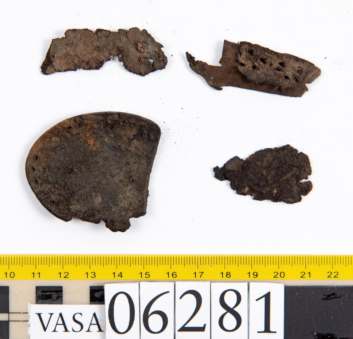 Delar och fragment av skobotten: klacklapp, del av sula samt tretton mindre fragment.

Klacklappen fyndnummer 06281, har hål efter två träpligg. Lädret är kraftigt. Del av sula med kvarsittande träpligg, fyndnummer 06281:1. Längs med sulans ytterkant löper dubbla rader av stygnshål. De fem fragmenten härrör troligtvis från sulor.

Lädret är rostfärgat och mycket sprött.