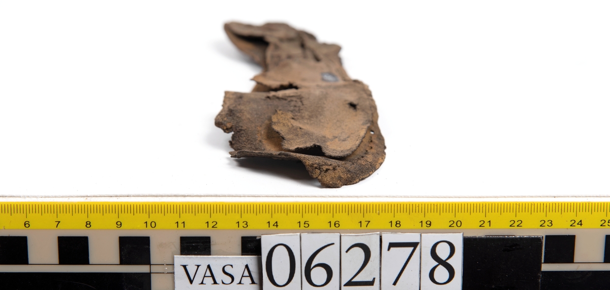 Sula, klacklapp samt större och mindre fragment från skobotten. Totalt ett 50-tal delar och fragment. Sulan är något fragmentarisk samt försedd med en ritsad linje som löper innanför ytterkanten. På klacklappen syns hål efter träpligg.
Klacklädret och sullädret är torrt och styvt medan en stor del av fragmenten består av mjukt och böjligt läder.