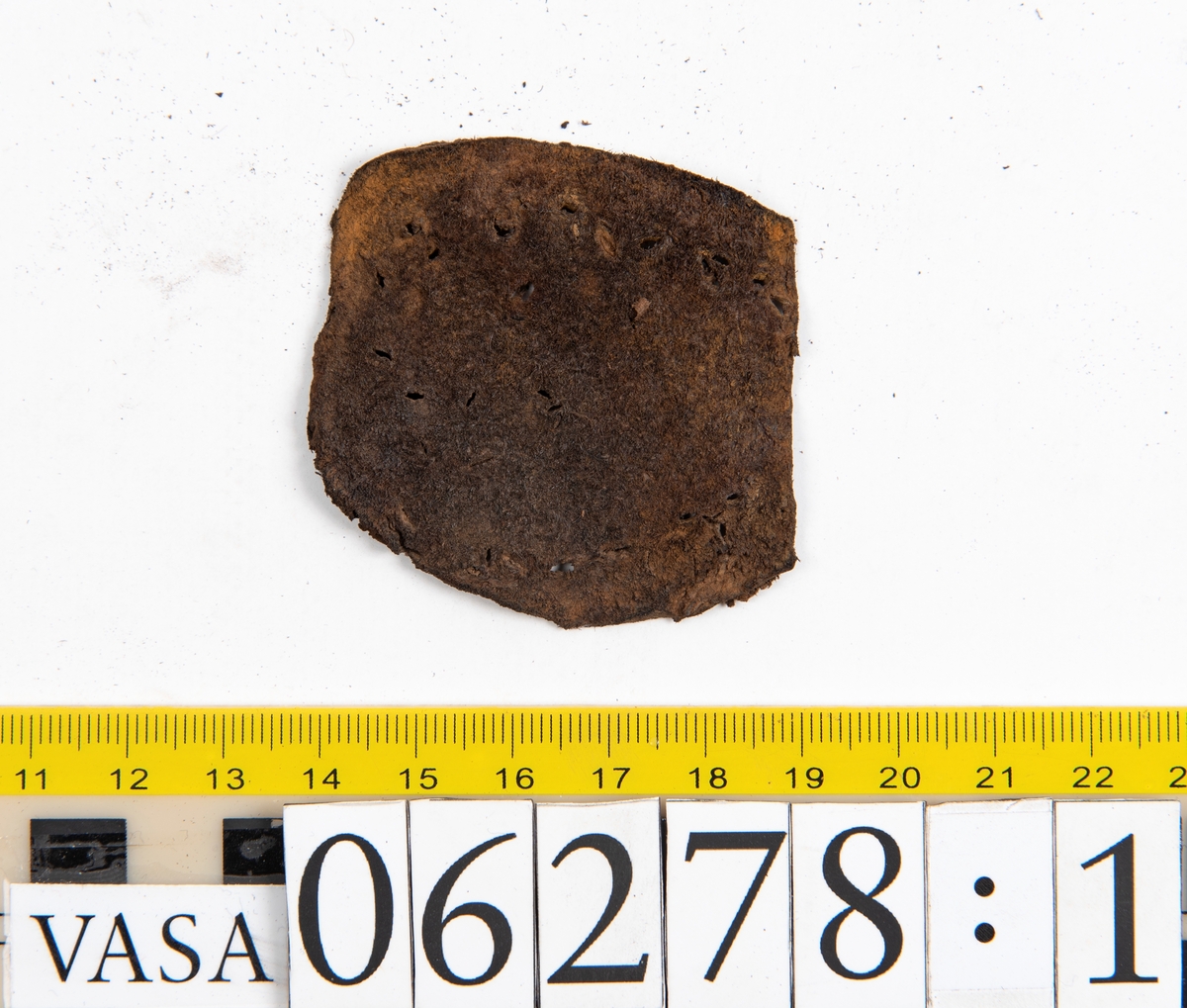 Sula, klacklapp samt större och mindre fragment från skobotten. Totalt ett 50-tal delar och fragment. Sulan är något fragmentarisk samt försedd med en ritsad linje som löper innanför ytterkanten. På klacklappen syns hål efter träpligg.
Klacklädret och sullädret är torrt och styvt medan en stor del av fragmenten består av mjukt och böjligt läder.
