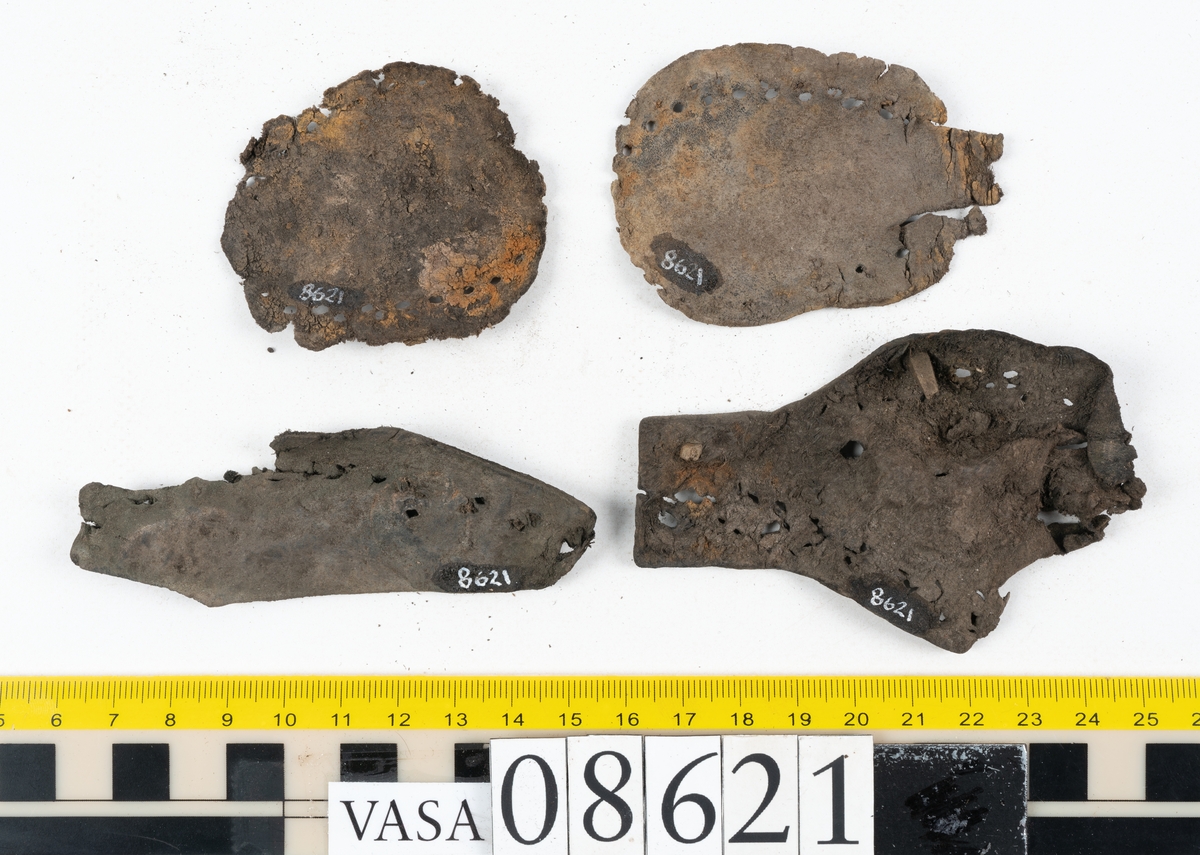 Delar och fragment från sko.
En fragmentarisk sula, fyndnummer 08621. Längs med ytterkanterna löper hål efter stygn. Lädret är spaltat och sprött.
En sula, fyndnummer 08621:1. Sulan är avskuren vid partiet för hålfoten. Sulan har hål efter stygn samt kvarsittande träpligg. Lädret är kraftigt.
En bakkappa, fyndnummer 08621:2. Bakkappan har suttit fästad på skons insida. Längs med ytterkanterna löper stygnshål med kvarsittande tråd.
Två klacklappar, fyndnummer 08621:3 och 08621:4. Klacklapparna har hål efter stygn och/eller träpligg.
Ett inlägg, fyndnummer 08621:5. Lädret är kraftigt.
Ett 100-tal fragment samt ytterligare två klacklappar och två inlägg.
En fragmentarisk bit tråd.
Tidigare även: Ett 15-tal fragment av textil. (Textilen fick ett eget fnr 27904 vid textildokumentationen 2015)