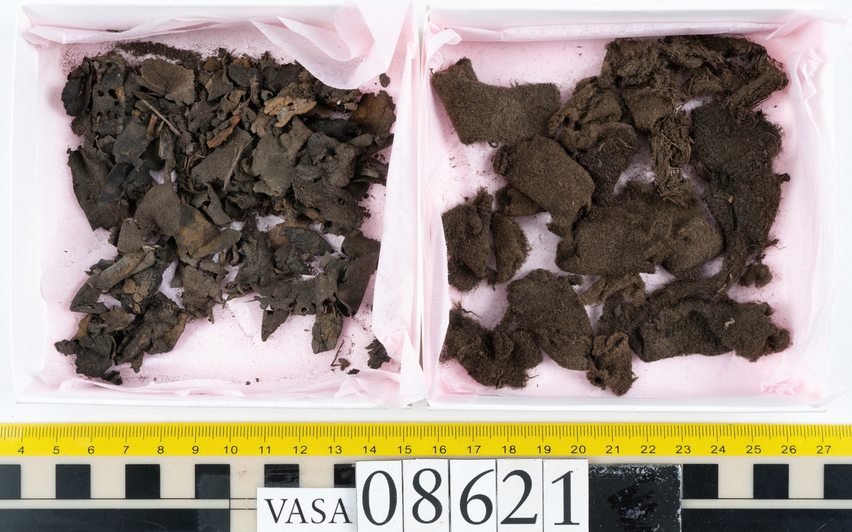 Delar och fragment från sko.
En fragmentarisk sula, fyndnummer 08621. Längs med ytterkanterna löper hål efter stygn. Lädret är spaltat och sprött.
En sula, fyndnummer 08621:1. Sulan är avskuren vid partiet för hålfoten. Sulan har hål efter stygn samt kvarsittande träpligg. Lädret är kraftigt.
En bakkappa, fyndnummer 08621:2. Bakkappan har suttit fästad på skons insida. Längs med ytterkanterna löper stygnshål med kvarsittande tråd.
Två klacklappar, fyndnummer 08621:3 och 08621:4. Klacklapparna har hål efter stygn och/eller träpligg.
Ett inlägg, fyndnummer 08621:5. Lädret är kraftigt.
Ett 100-tal fragment samt ytterligare två klacklappar och två inlägg.
En fragmentarisk bit tråd.
Tidigare även: Ett 15-tal fragment av textil. (Textilen fick ett eget fnr 27904 vid textildokumentationen 2015)