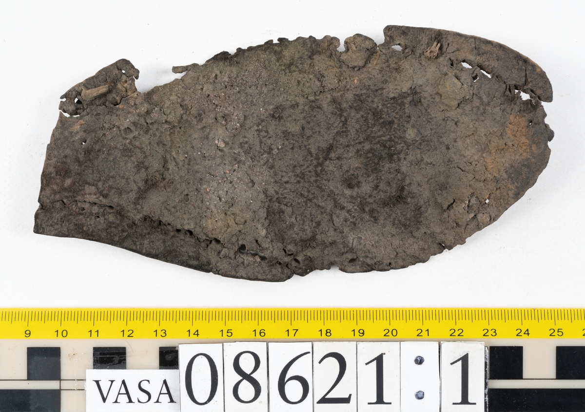Delar och fragment från sko.
En fragmentarisk sula, fyndnummer 08621. Längs med ytterkanterna löper hål efter stygn. Lädret är spaltat och sprött.
En sula, fyndnummer 08621:1. Sulan är avskuren vid partiet för hålfoten. Sulan har hål efter stygn samt kvarsittande träpligg. Lädret är kraftigt.
En bakkappa, fyndnummer 08621:2. Bakkappan har suttit fästad på skons insida. Längs med ytterkanterna löper stygnshål med kvarsittande tråd.
Två klacklappar, fyndnummer 08621:3 och 08621:4. Klacklapparna har hål efter stygn och/eller träpligg.
Ett inlägg, fyndnummer 08621:5. Lädret är kraftigt.
Ett 100-tal fragment samt ytterligare två klacklappar och två inlägg.
En fragmentarisk bit tråd.
Tidigare även: Ett 15-tal fragment av textil. (Textilen fick ett eget fnr 27904 vid textildokumentationen 2015)