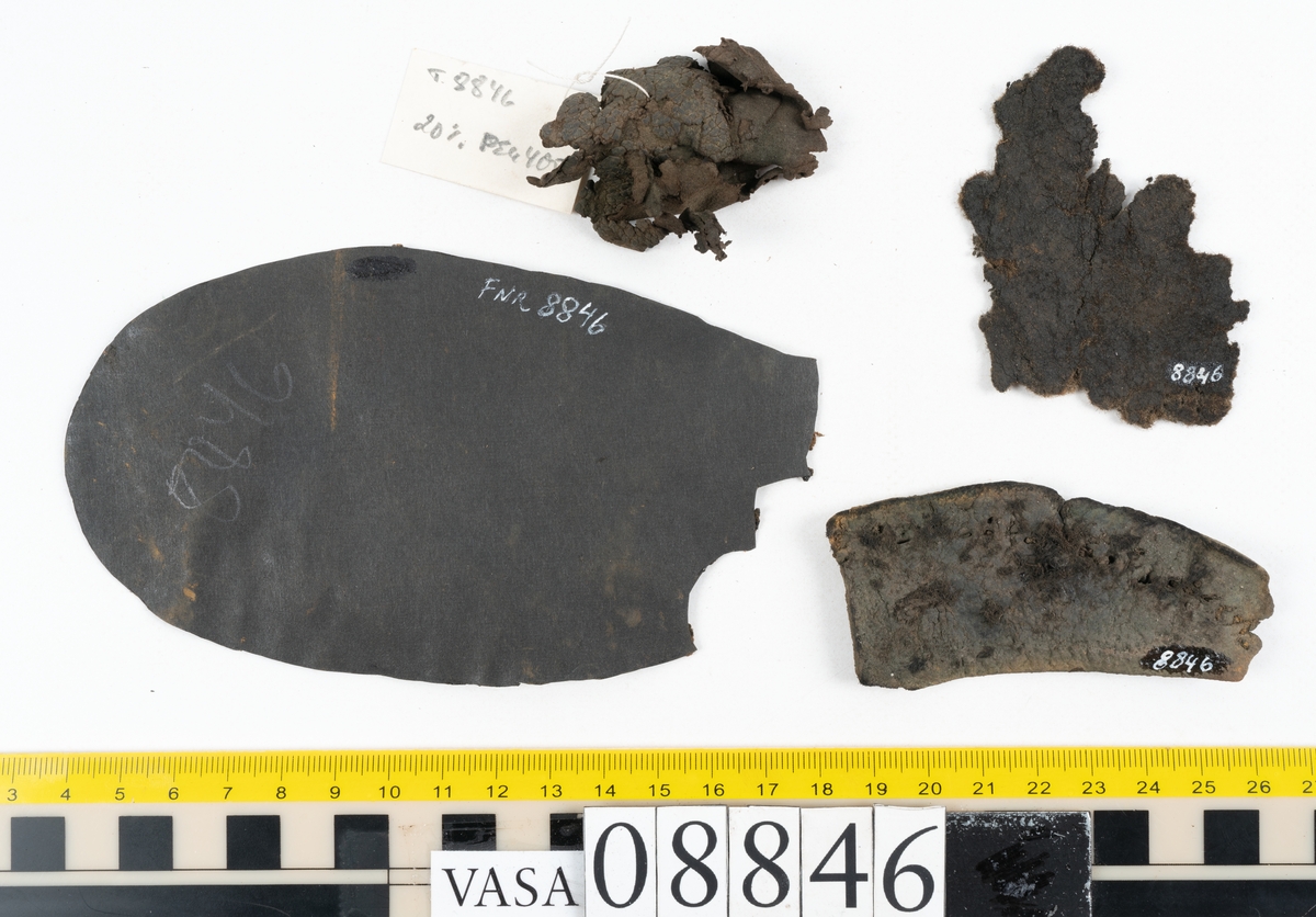 Läder samt en bit filtad textil.

Dokumentation 1996:
Delar av botten till holtrandsydd sko: del av botten, främre partiet av en löst liggande sula, två fragment, en laglapp samt skopligg.
Skobottnen består av en hel yttersula på vilken fyra klacklappar sitterfästade. Yttersulan har en ritsad linje som löper ca 5-15 mm in från sulkanten. På yttersulan sitter delar av sulor, troligtvis laglappar eller någon form av sulförstärkning, fästade med träpligg. Klacken består av fyra klacklappar. Mellan två av klacklapparna har en mindre kilformad lapp infogats. På klackbottnen sitter ett flertal större laglappar fästade med träpligg.
Den löst liggande delen av sulan är monterat på svart kartong.

Dokumentation 2022:
Skobotten. Tillverkad i läder. Skapades på en rak läst och bars på höger fot. Inga dekorationer. Den är sliten och har hål i yttersulan. Det finns tecken på att bäraren supinerade. Det finns spår av ett flertal lagningar med träpligg och en höjning av klacken. 
För mer information, se Uppritning under Länkade filer.

Text in english:
This is the bottom unit of shoe, made of leather, made on a straight last and worn on the right foot, with no decorative features. The bottom unit is worn, has small holes in the outer sole, and shows signs of supination. There have been extensive repairs including pegged repairs and a heel lift.
For more information, go to Länkade filer: Uppritning
