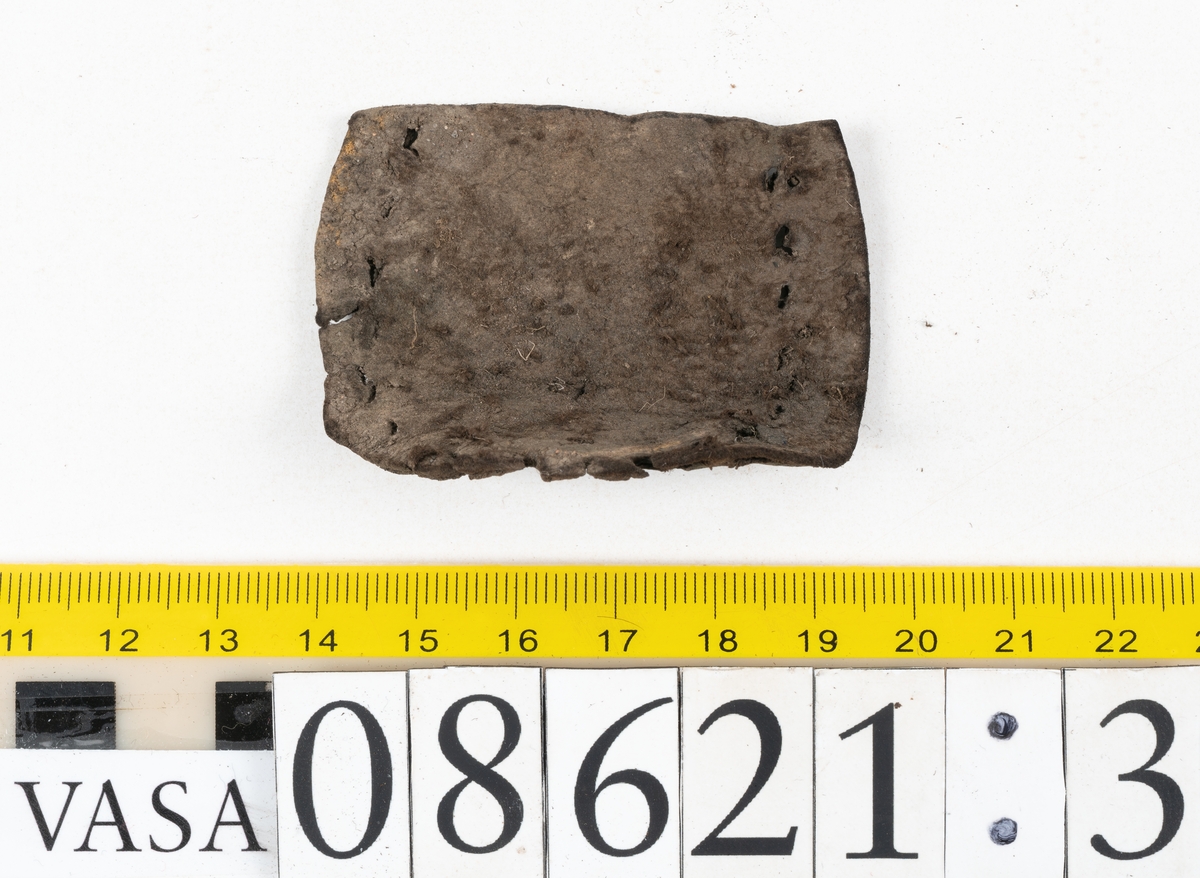 Delar och fragment från sko.
En fragmentarisk sula, fyndnummer 08621. Längs med ytterkanterna löper hål efter stygn. Lädret är spaltat och sprött.
En sula, fyndnummer 08621:1. Sulan är avskuren vid partiet för hålfoten. Sulan har hål efter stygn samt kvarsittande träpligg. Lädret är kraftigt.
En bakkappa, fyndnummer 08621:2. Bakkappan har suttit fästad på skons insida. Längs med ytterkanterna löper stygnshål med kvarsittande tråd.
Två klacklappar, fyndnummer 08621:3 och 08621:4. Klacklapparna har hål efter stygn och/eller träpligg.
Ett inlägg, fyndnummer 08621:5. Lädret är kraftigt.
Ett 100-tal fragment samt ytterligare två klacklappar och två inlägg.
En fragmentarisk bit tråd.
Tidigare även: Ett 15-tal fragment av textil. (Textilen fick ett eget fnr 27904 vid textildokumentationen 2015)