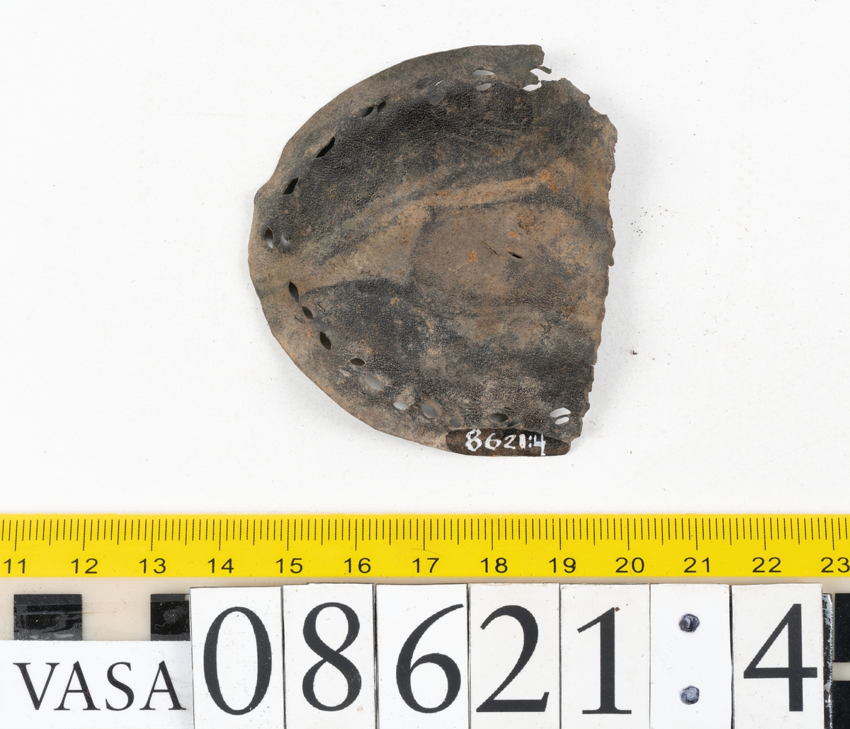 Delar och fragment från sko.
En fragmentarisk sula, fyndnummer 08621. Längs med ytterkanterna löper hål efter stygn. Lädret är spaltat och sprött.
En sula, fyndnummer 08621:1. Sulan är avskuren vid partiet för hålfoten. Sulan har hål efter stygn samt kvarsittande träpligg. Lädret är kraftigt.
En bakkappa, fyndnummer 08621:2. Bakkappan har suttit fästad på skons insida. Längs med ytterkanterna löper stygnshål med kvarsittande tråd.
Två klacklappar, fyndnummer 08621:3 och 08621:4. Klacklapparna har hål efter stygn och/eller träpligg.
Ett inlägg, fyndnummer 08621:5. Lädret är kraftigt.
Ett 100-tal fragment samt ytterligare två klacklappar och två inlägg.
En fragmentarisk bit tråd.
Tidigare även: Ett 15-tal fragment av textil. (Textilen fick ett eget fnr 27904 vid textildokumentationen 2015)