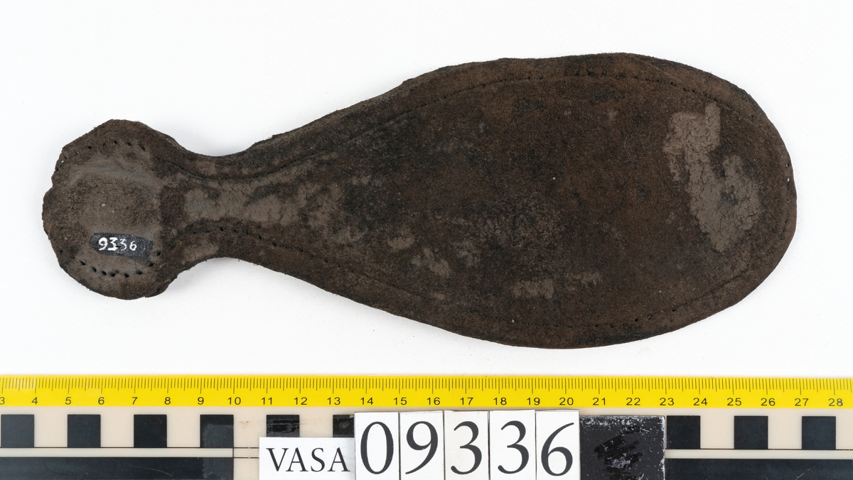 Fyra delar från sko: en sula, ett sidostycke med slejf samt två ospecificerade fragment.

En ritsad linje löper strax innanför sulans ytterkant. På sulans köttsida finns kvarsittande tråd. I änden på sidostyckets slejf syns ett runt hål med en nedskärning. På sidostycket syns kvarsittande tråd. Lädret är kraftigt.