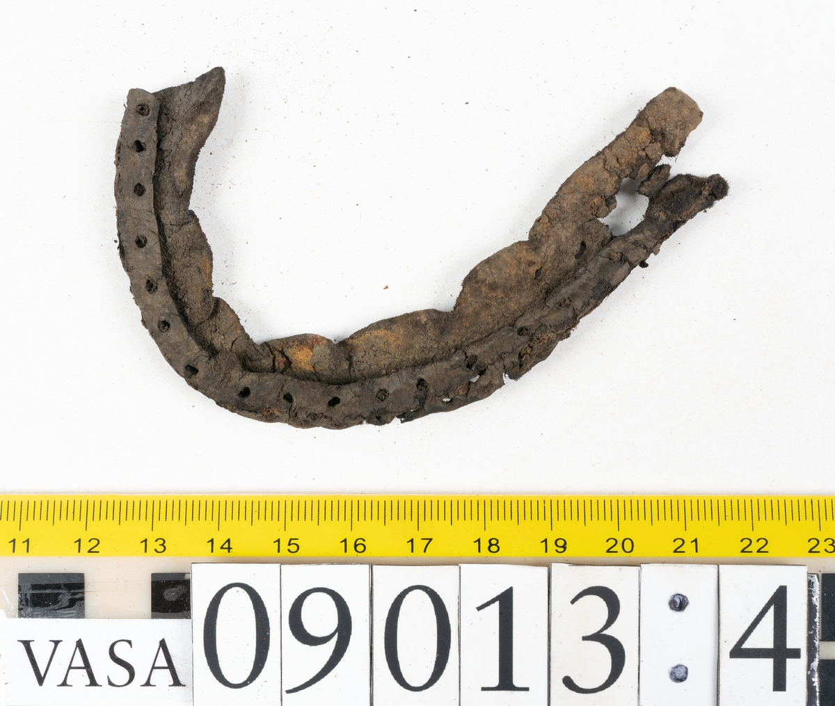 Delar och fragment från skor: bakappa, holtrand, klacklappar, delar av sulor och inlägg mm.

Främre partiet av en sula, fyndnummer 09013. Hål efter stygn och pligg. Kvarsittande träpligg. Narvsidan är något sprucken. Lädret är kraftigt.

Klacklapp, eventuellt laglapp till tåparti, fyndnummer 09013:1. Kvarsittande träpligg. Lädret är spaltat och fragmentariskt samt har rostliknande utfällningar.

Främre partiet av skobotten eller sula, fyndnummer 09013:2. Kvarsittande tråd. Lädret är sprött och spaltat samt har rostliknande utfällningar.

Bakkappa, fyndnummer 09013:3. Längs med ytterkanterna löper hål efter stygn. Lädret är kraftigt och narvytan är välbevarad.

Två holtrander, fyndnummer 09013:4 samt 09013:5. Holtranderna är dubbelvikta samt har hål efter stygn. Holtranderna härrör från två skobottnar.

En bit av ett filtliknande material. Troligtvis har filtbiten fungerat som inlägg. Filtbiten är spröd och fragmentarisk. 
Fyndet innehåller även ytterligare textilfragment.

Ett 30-tal större delar samt en stor mängd mycket små fragment.