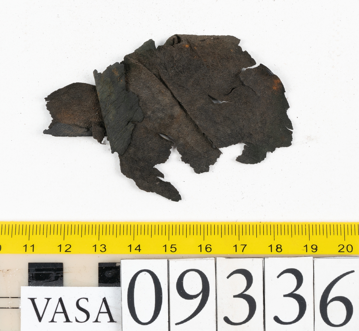 Fyra delar från sko: en sula, ett sidostycke med slejf samt två ospecificerade fragment.

En ritsad linje löper strax innanför sulans ytterkant. På sulans köttsida finns kvarsittande tråd. I änden på sidostyckets slejf syns ett runt hål med en nedskärning. På sidostycket syns kvarsittande tråd. Lädret är kraftigt.