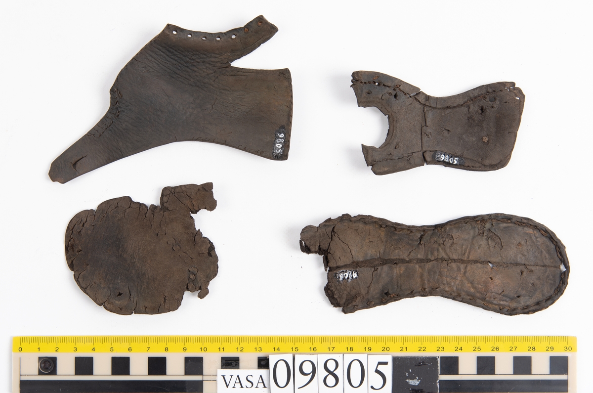 Ett 60-tal delar och fragment från sko: sulor, sidostycke, delar från klack m.m. samt ett filtfragment. Bland delarna kan urskiljas en klacklapp med kvarsittande skopligg samt ett sidostycke med slejf. I slejfänden finns ett hål - troligtvis knapphål.

Delar av lädret är kraftigt och välbevarat medan andra delar är spaltade samt har rostliknande utfällningar.