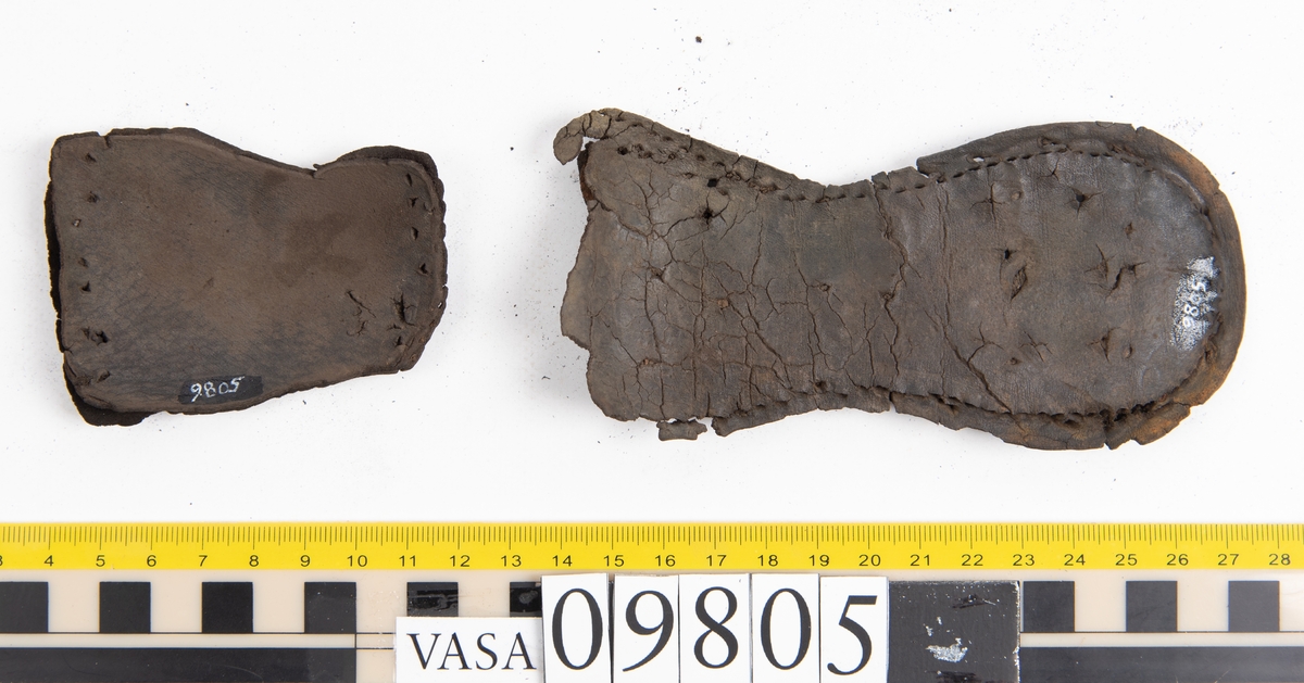 Ett 60-tal delar och fragment från sko: sulor, sidostycke, delar från klack m.m. samt ett filtfragment. Bland delarna kan urskiljas en klacklapp med kvarsittande skopligg samt ett sidostycke med slejf. I slejfänden finns ett hål - troligtvis knapphål.

Delar av lädret är kraftigt och välbevarat medan andra delar är spaltade samt har rostliknande utfällningar.