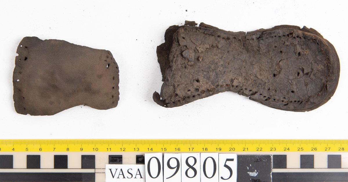 Ett 60-tal delar och fragment från sko: sulor, sidostycke, delar från klack m.m. samt ett filtfragment. Bland delarna kan urskiljas en klacklapp med kvarsittande skopligg samt ett sidostycke med slejf. I slejfänden finns ett hål - troligtvis knapphål.

Delar av lädret är kraftigt och välbevarat medan andra delar är spaltade samt har rostliknande utfällningar.