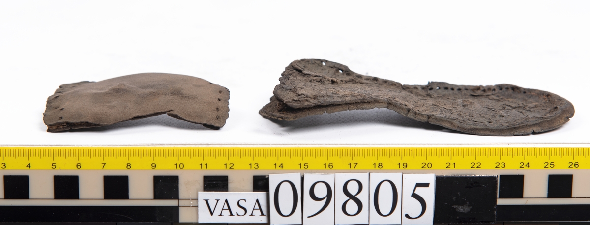 Ett 60-tal delar och fragment från sko: sulor, sidostycke, delar från klack m.m. samt ett filtfragment. Bland delarna kan urskiljas en klacklapp med kvarsittande skopligg samt ett sidostycke med slejf. I slejfänden finns ett hål - troligtvis knapphål.

Delar av lädret är kraftigt och välbevarat medan andra delar är spaltade samt har rostliknande utfällningar.