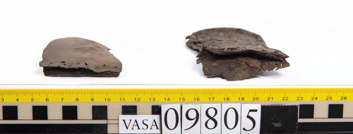 Ett 60-tal delar och fragment från sko: sulor, sidostycke, delar från klack m.m. samt ett filtfragment. Bland delarna kan urskiljas en klacklapp med kvarsittande skopligg samt ett sidostycke med slejf. I slejfänden finns ett hål - troligtvis knapphål.

Delar av lädret är kraftigt och välbevarat medan andra delar är spaltade samt har rostliknande utfällningar.