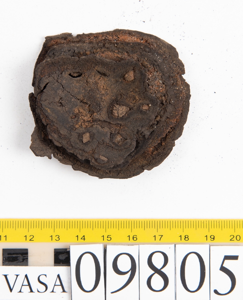Ett 60-tal delar och fragment från sko: sulor, sidostycke, delar från klack m.m. samt ett filtfragment. Bland delarna kan urskiljas en klacklapp med kvarsittande skopligg samt ett sidostycke med slejf. I slejfänden finns ett hål - troligtvis knapphål.

Delar av lädret är kraftigt och välbevarat medan andra delar är spaltade samt har rostliknande utfällningar.