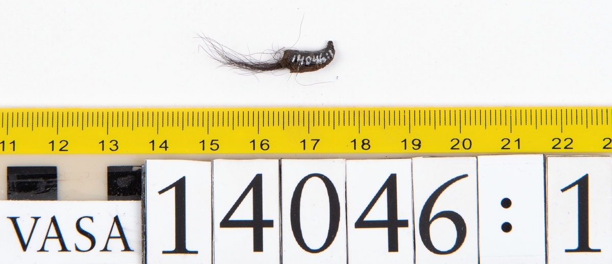 Tjugo ospecificerade läderbitar samt ett flertal mycket små fragment. På två av fragmenten, fyndnummer 14046:1 samt 14046:7, finns svarta hårstrån, ca 5-20 mm långa. Lädret saknar hål efter stygn eller träpligg.