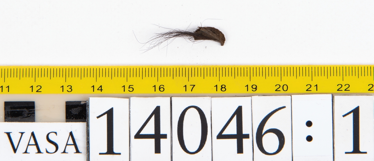 Tjugo ospecificerade läderbitar samt ett flertal mycket små fragment. På två av fragmenten, fyndnummer 14046:1 samt 14046:7, finns svarta hårstrån, ca 5-20 mm långa. Lädret saknar hål efter stygn eller träpligg.