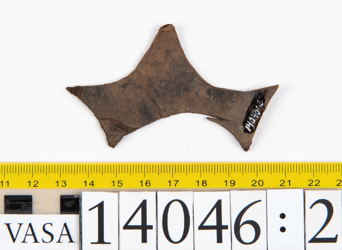 Tjugo ospecificerade läderbitar samt ett flertal mycket små fragment. På två av fragmenten, fyndnummer 14046:1 samt 14046:7, finns svarta hårstrån, ca 5-20 mm långa. Lädret saknar hål efter stygn eller träpligg.