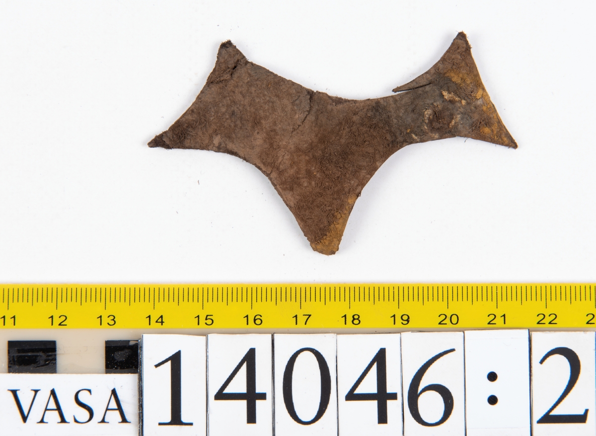 Tjugo ospecificerade läderbitar samt ett flertal mycket små fragment. På två av fragmenten, fyndnummer 14046:1 samt 14046:7, finns svarta hårstrån, ca 5-20 mm långa. Lädret saknar hål efter stygn eller träpligg.