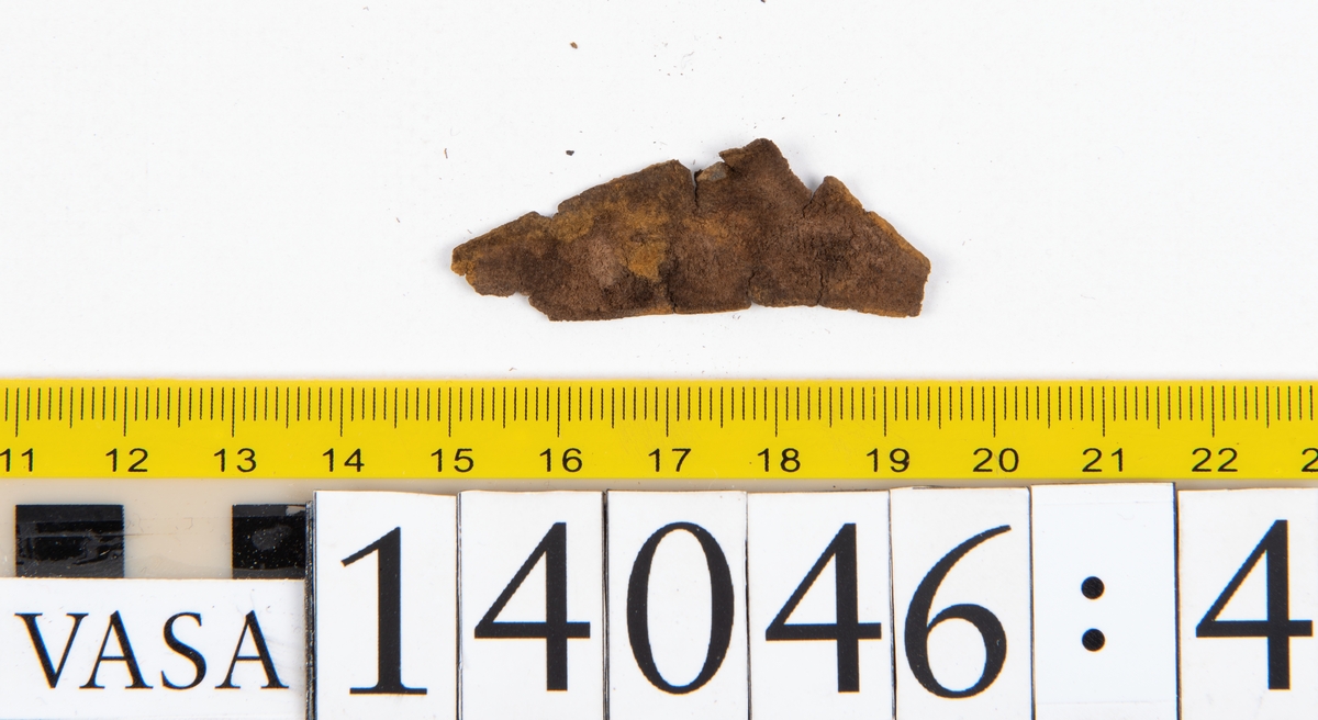 Tjugo ospecificerade läderbitar samt ett flertal mycket små fragment. På två av fragmenten, fyndnummer 14046:1 samt 14046:7, finns svarta hårstrån, ca 5-20 mm långa. Lädret saknar hål efter stygn eller träpligg.