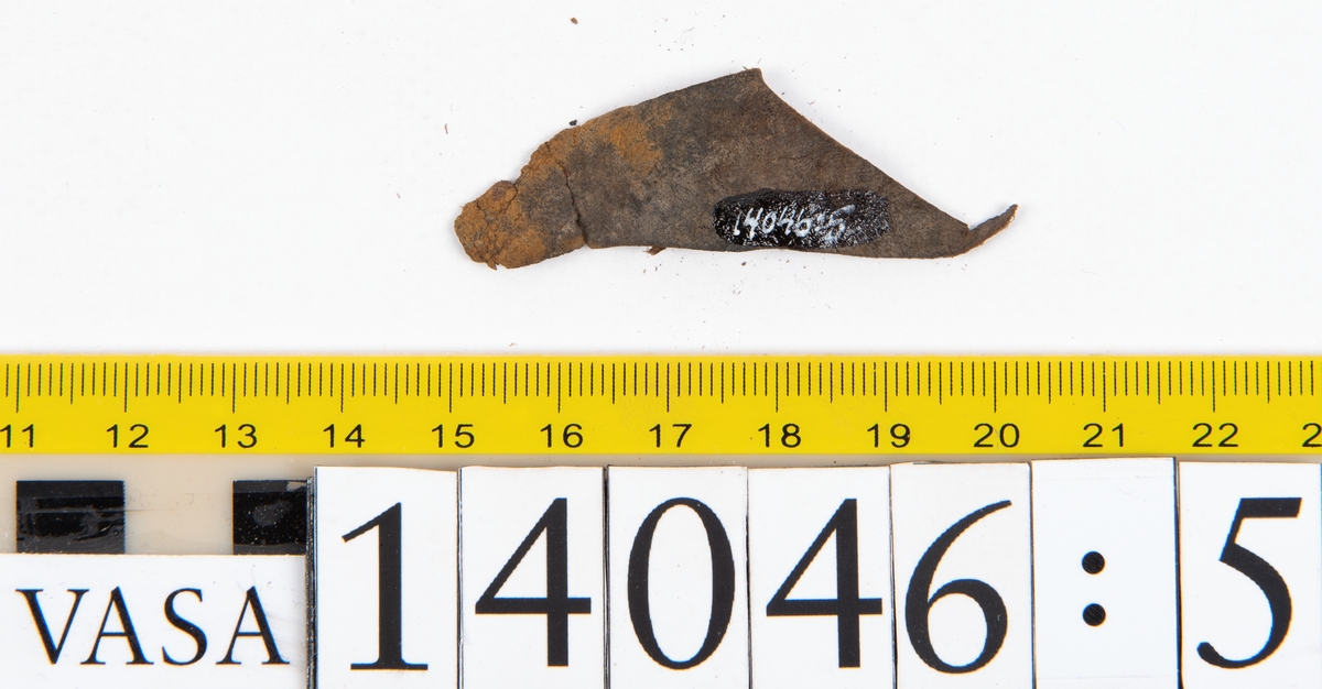 Tjugo ospecificerade läderbitar samt ett flertal mycket små fragment. På två av fragmenten, fyndnummer 14046:1 samt 14046:7, finns svarta hårstrån, ca 5-20 mm långa. Lädret saknar hål efter stygn eller träpligg.
