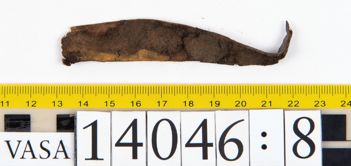 Tjugo ospecificerade läderbitar samt ett flertal mycket små fragment. På två av fragmenten, fyndnummer 14046:1 samt 14046:7, finns svarta hårstrån, ca 5-20 mm långa. Lädret saknar hål efter stygn eller träpligg.