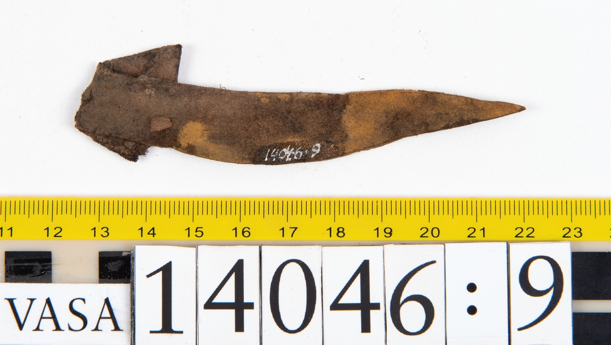 Tjugo ospecificerade läderbitar samt ett flertal mycket små fragment. På två av fragmenten, fyndnummer 14046:1 samt 14046:7, finns svarta hårstrån, ca 5-20 mm långa. Lädret saknar hål efter stygn eller träpligg.