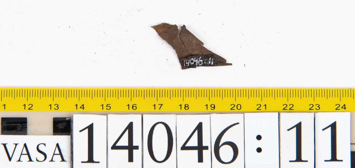 Tjugo ospecificerade läderbitar samt ett flertal mycket små fragment. På två av fragmenten, fyndnummer 14046:1 samt 14046:7, finns svarta hårstrån, ca 5-20 mm långa. Lädret saknar hål efter stygn eller träpligg.