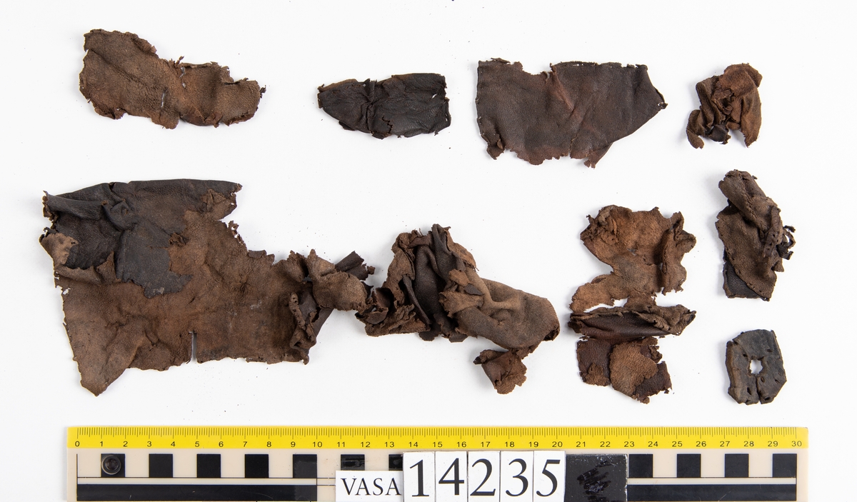 Ett 60-tal fragment från handske. På flera av fragmenten finns hål efter stygn. Lädret är mycket mjukt, tunt och sprött.