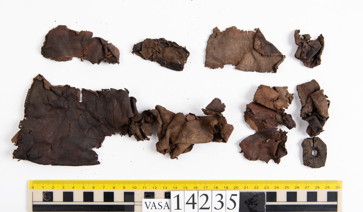 Ett 60-tal fragment från handske. På flera av fragmenten finns hål efter stygn. Lädret är mycket mjukt, tunt och sprött.