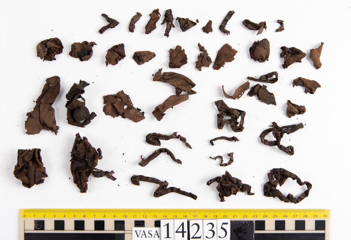 Ett 60-tal fragment från handske. På flera av fragmenten finns hål efter stygn. Lädret är mycket mjukt, tunt och sprött.