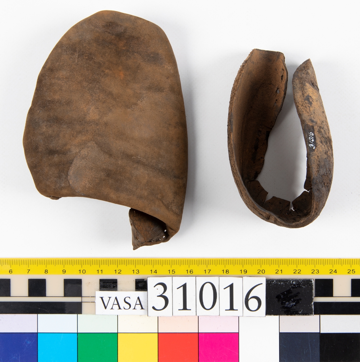 Ovanläder och bakkappa till sko. Längs med ovanlädrets ytterkant löper en enkel rad med stygnshål. Narvytan är välbevarad och har en rutmönstrad struktur. Bakkappans nedre kant är vikt. Kanten har legat invikt och suttit fästad i sulpaketet.