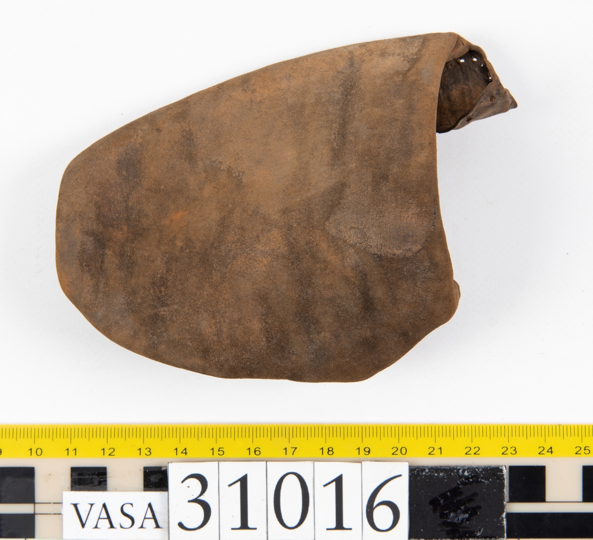 Ovanläder och bakkappa till sko. Längs med ovanlädrets ytterkant löper en enkel rad med stygnshål. Narvytan är välbevarad och har en rutmönstrad struktur. Bakkappans nedre kant är vikt. Kanten har legat invikt och suttit fästad i sulpaketet.