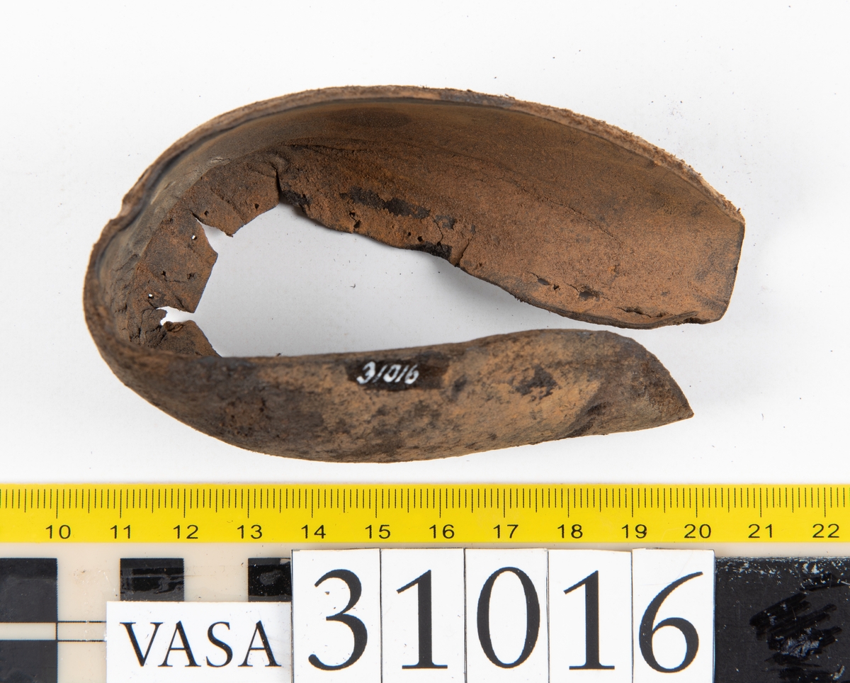 Ovanläder och bakkappa till sko. Längs med ovanlädrets ytterkant löper en enkel rad med stygnshål. Narvytan är välbevarad och har en rutmönstrad struktur. Bakkappans nedre kant är vikt. Kanten har legat invikt och suttit fästad i sulpaketet.