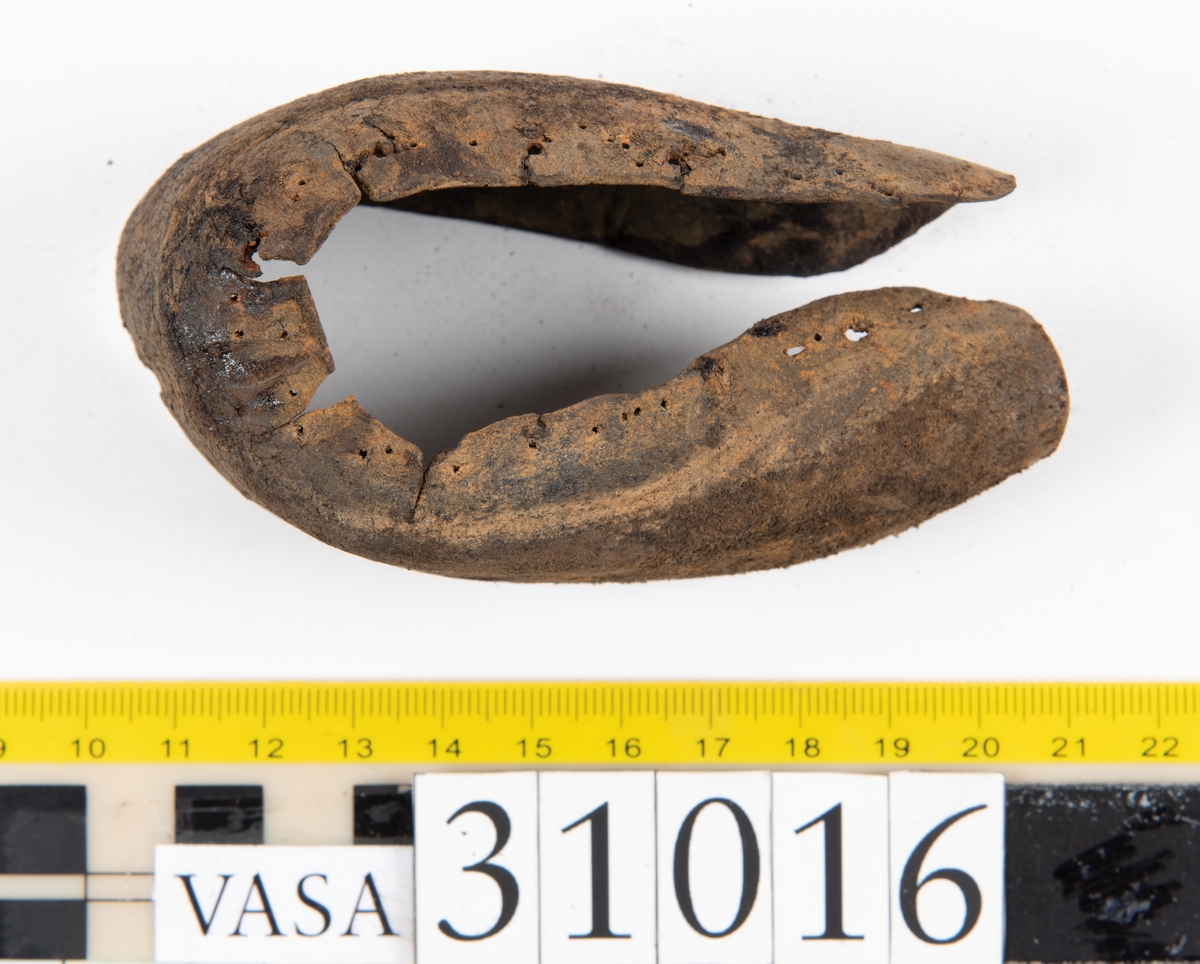 Ovanläder och bakkappa till sko. Längs med ovanlädrets ytterkant löper en enkel rad med stygnshål. Narvytan är välbevarad och har en rutmönstrad struktur. Bakkappans nedre kant är vikt. Kanten har legat invikt och suttit fästad i sulpaketet.